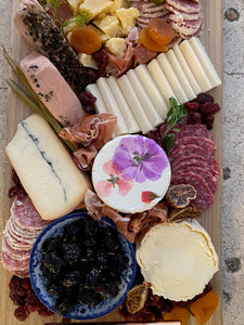 cheese and charcuterie board with assorted cheeses, olives and meats. 