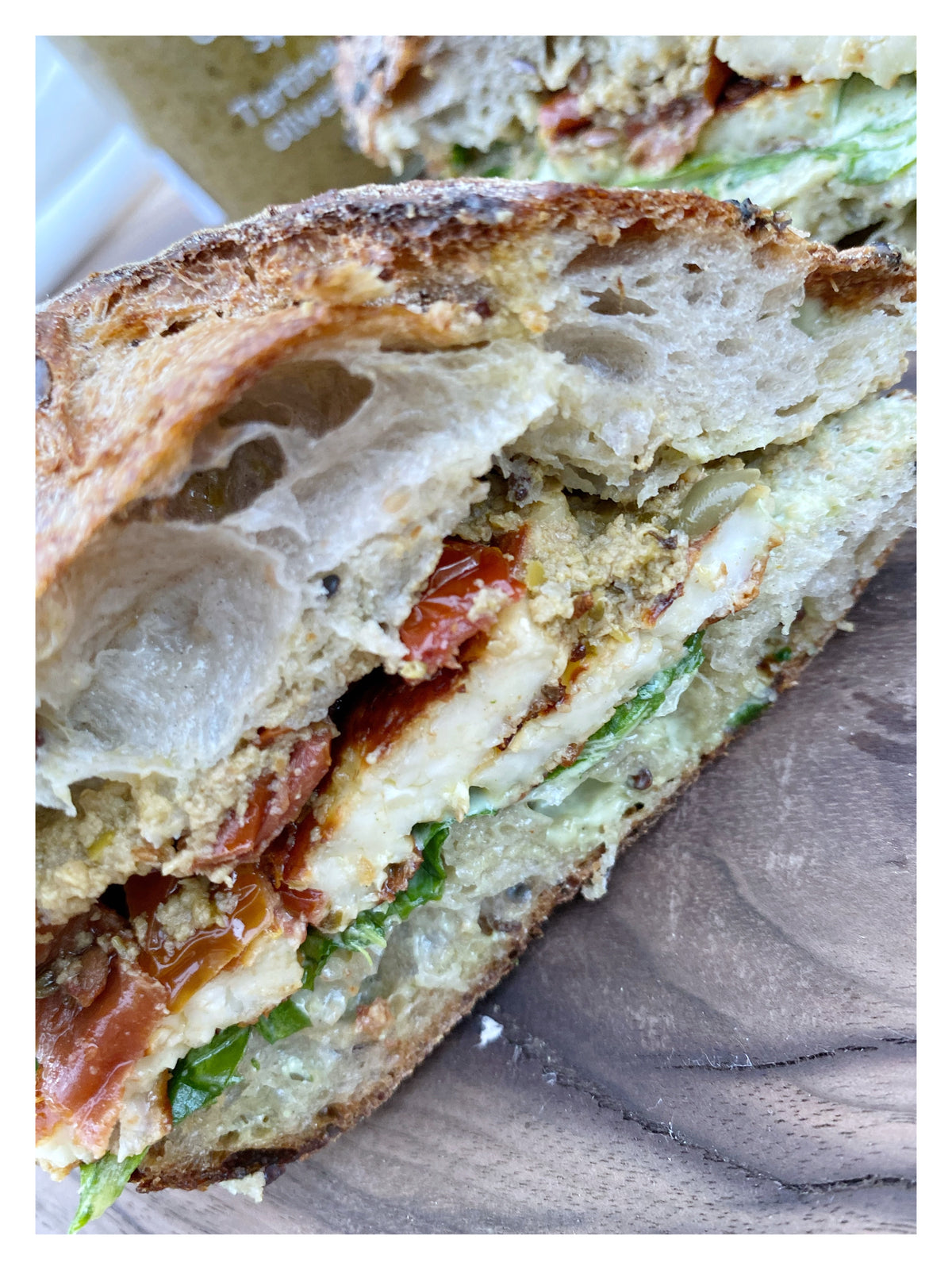 baguette sandwich with halloumi, sun-dried tomatoes, arugula, green olive spread, basil aioli 