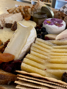 close up of cheese and charcuterie board with assorted cheeses, breads and meats. 